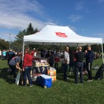 More volunteers standing outside under a white tent with food and beverages.