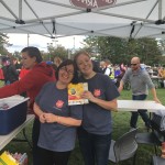 Volunteers smile for a photo under the white tent, at the park.