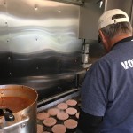 Hamburgers being cooked by food service volunteers.