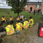 A salvation army worker speaks to a group of emergency workers under a tree