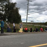 People sitting on the ground eating. lunch near a tornado relief area