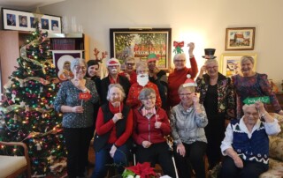 ladies enjoy fellowship at a Christmas party posing with props and a christmas tree